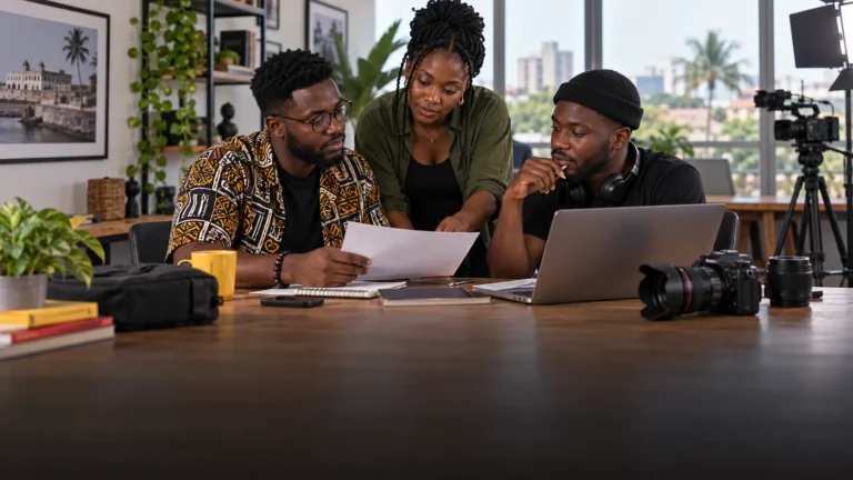 A Ghanaian photographer, writer and video producer reviewing a modest collaboration brief together in a shared creative workspace