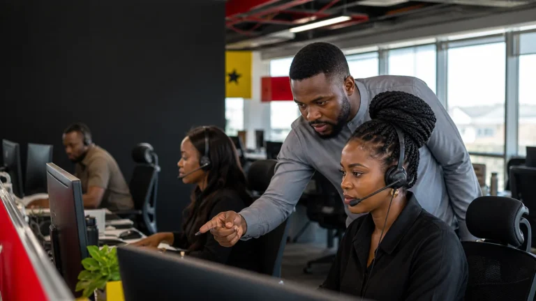Ghanaian contact centre team leader coaching an agent at a workstation